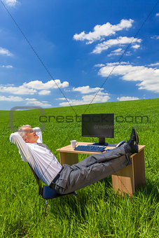 Businessman Relaxing Feet Up Desk in Green Field