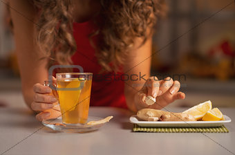 Closeup on young woman adding cane sugar cube in ginger tea