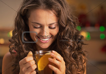 Happy young woman enjoying drinking ginger tea with lemon