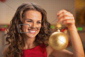 Happy young woman in red dress holding christmas ball