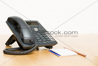 phone on desk with notepad on wooden desk