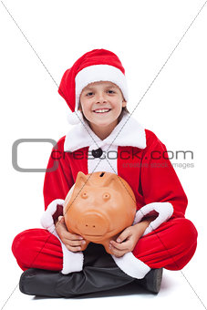 Happy boy in santa costume with piggy bank