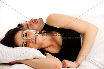 Woman laid in white bed next to a sleeping man