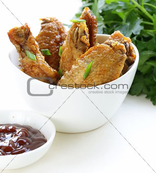 Fried chicken wings with hot  sauce in a white bowl