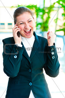 Young brunette enjoys success with the phone on office background