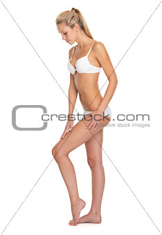 Full length portrait of young woman in lingerie touching leg