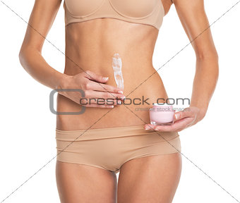 Closeup on young woman in lingerie applying creme on belly