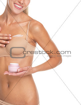 Closeup on young woman in lingerie applying creme on breast