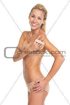 Happy young woman in lingerie using massager on arm