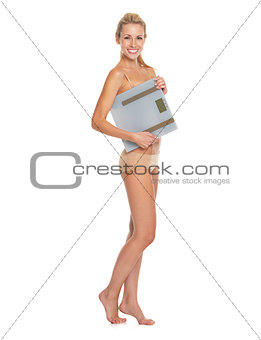 Full length portrait of smiling young woman in lingerie holding 