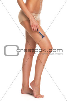 Closeup on woman in lingerie shaving legs using disposable razor