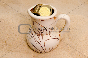 jug with coins in sand