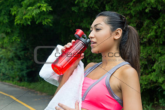 Woman drinks water and rests after running
