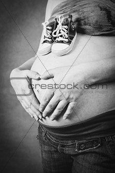 pregnant woman with a child shoe and hand heart shape