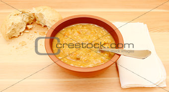 Soup on a table with a torn bread roll