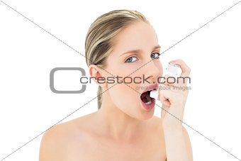 Natural fresh blonde woman using asthma inhaler
