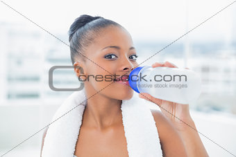 Smiling woman with towel around her neck drinking water