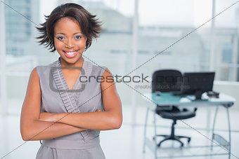 Smiling businesswoman standing in office and crossing her arms