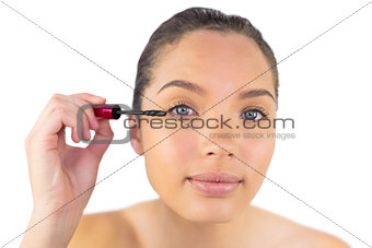 Happy woman using mascara for her eyelashes