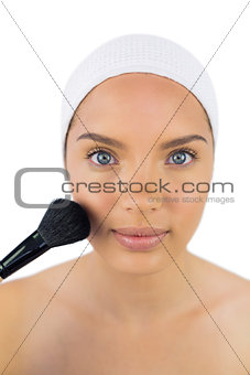 Pretty woman wearing headband using powder brush