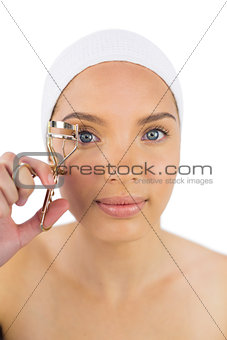 Attractive woman with headband using eyelash curler