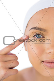 Attractive woman with headband on putting cream on her face