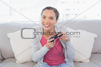Happy woman sitting on sofa playing video games
