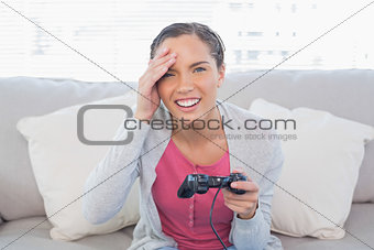 Irritated pretty woman sitting on sofa playing video games