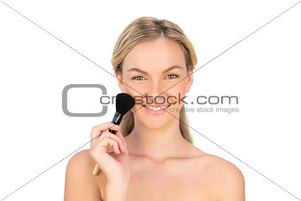 Smiling pretty bare blonde using powder brush