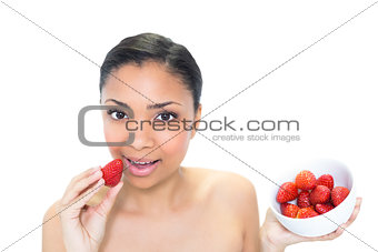 Relaxed young dark haired model eating strawberries