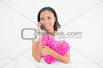 Pretty young dark haired model holding a pillow and making a phone call