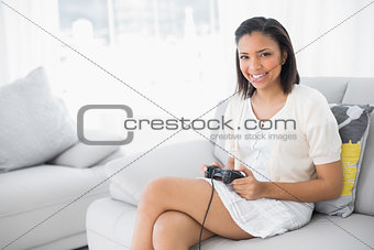 Content young dark haired woman in white clothes playing video games