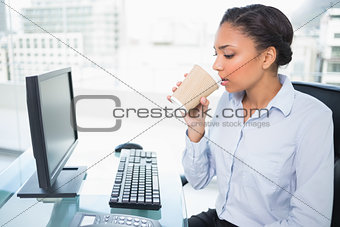 Relaxed young dark haired businesswoman drinking coffee