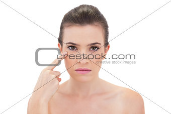 Serious natural brown haired model touching her cheekbone