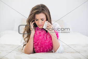 Upset casual brown haired woman in white pajamas making a phone call