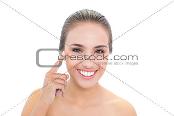 Smiling brunette woman pointing at her eye