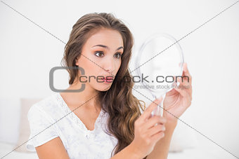 Surprised attractive brunette looking at mirror