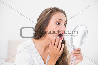 Attractive brunette opening mouth and looking at mirror
