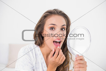 Attractive brunette opening mouth and holding mirror