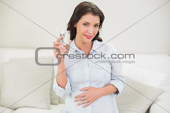 Pleased pregnant brown haired woman drinking water