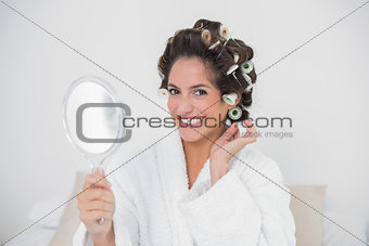 Smiling natural brunette holding hand mirror