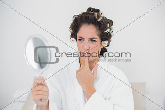 Pensive natural brunette looking at mirror
