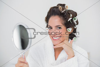 Happy natural brunette holding hand mirror