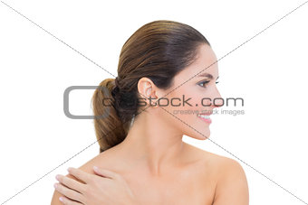 Cheerful bare brunette turning head right