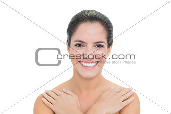 Cheerful bare brunette touching both shoulders
