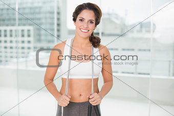 Sporty smiling brunette holding skipping rope