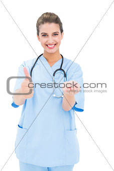 Joyful brown haired nurse in blue scrubs advising a pill
