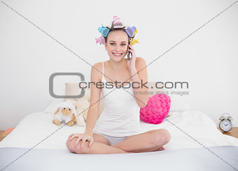 Happy natural brown haired woman in hair curlers making a phone call