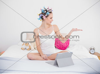 Peaceful natural brown haired woman in hair curlers posing with an arm raised