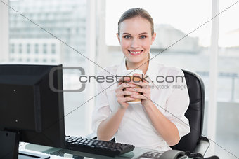 Businesswoman holding disposable cup smiling at camera